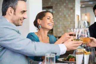 Eine Gruppe von Freunden, die an einem Tisch anstoßen und lachen.