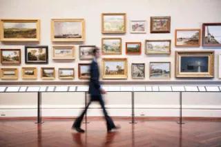 Ein Besucher geht durch eine Kunstgalerie mit verschiedenen Gemälden.