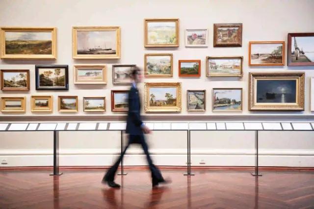 Ein Besucher geht durch eine Kunstgalerie mit verschiedenen Gemälden.