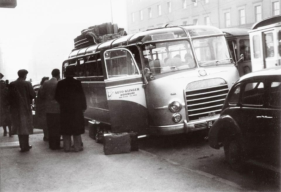 Historischer Reisebus mit Gepäck auf dem Dach in einer Stadt