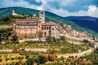 Panoramablick auf die Stadt Assisi mit historischen Gebäuden und Bergen im Hintergrund.