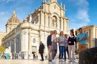 Eine Gruppe von Touristen steht vor einer historischen Kirche in Sizilien.