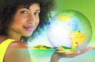 Eine Frau hält eine Weltkugel mit einer grünen Landschaft im Hintergrund.
