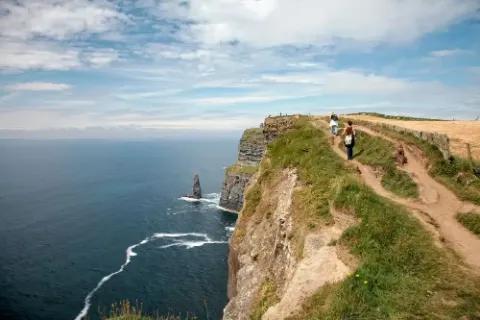 Zwei Wanderer auf den Klippen mit Blick auf das Meer.