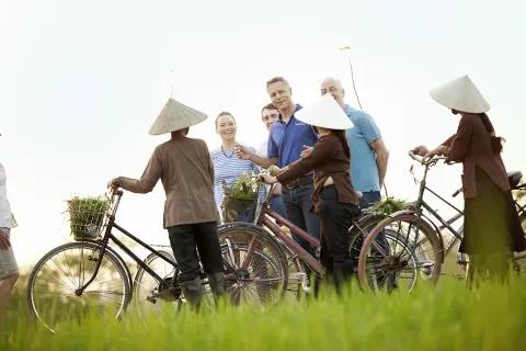 Eine Gruppe von Menschen, die in einem Feld mit Fahrrädern stehen.