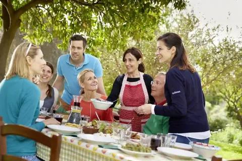 Eine fröhliche Gruppe von Menschen genießt ein gemeinsames Essen im Garten.