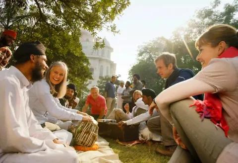 Gruppen von Menschen, die im Park miteinander lachen und musizieren.