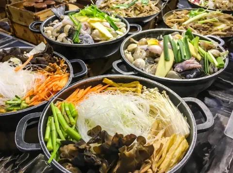 Eine Pfanne voller Zutaten für asiatische Gerichte, einschließlich Gemüse und Nudeln.