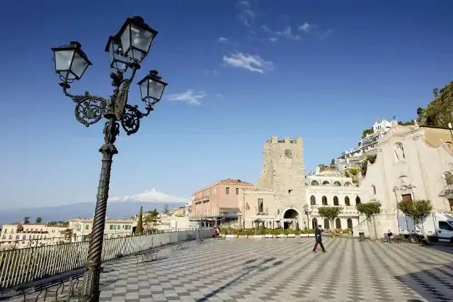 Blick auf den Platz in Taormina auf Sizilien mit historischen Gebäuden und einem Laternenpfahl.