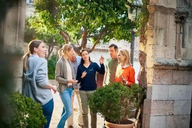 Eine Gruppe von Menschen diskutiert im Freien unter Bäumen.