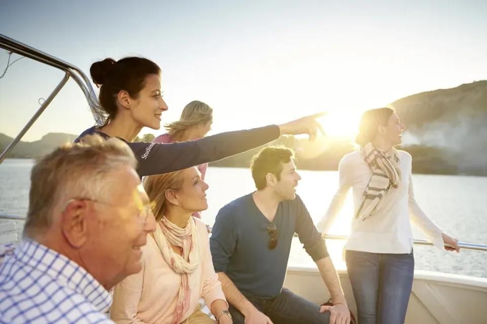 Eine Gruppe von Menschen bei einer Bootsfahrt am Sonnenuntergang.