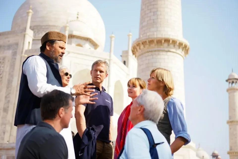 Touristen hören einem Reiseführer am Taj Mahal in Indien zu.