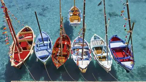 Traditionelle Fischerboote in leuchtenden Farben im Hafen. Dies und viel mehr sehen Sie auf unserer smart&small-Reise nach Apulien.