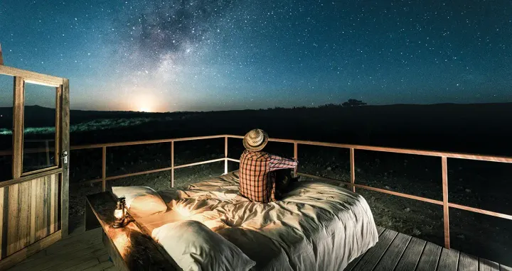 Ein Mann schaut von einer Dachterrasse in den Sternenhimmel Namibias